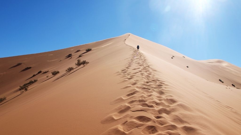 Duna del desierto del Sahara con un viajero subiendo la cresta